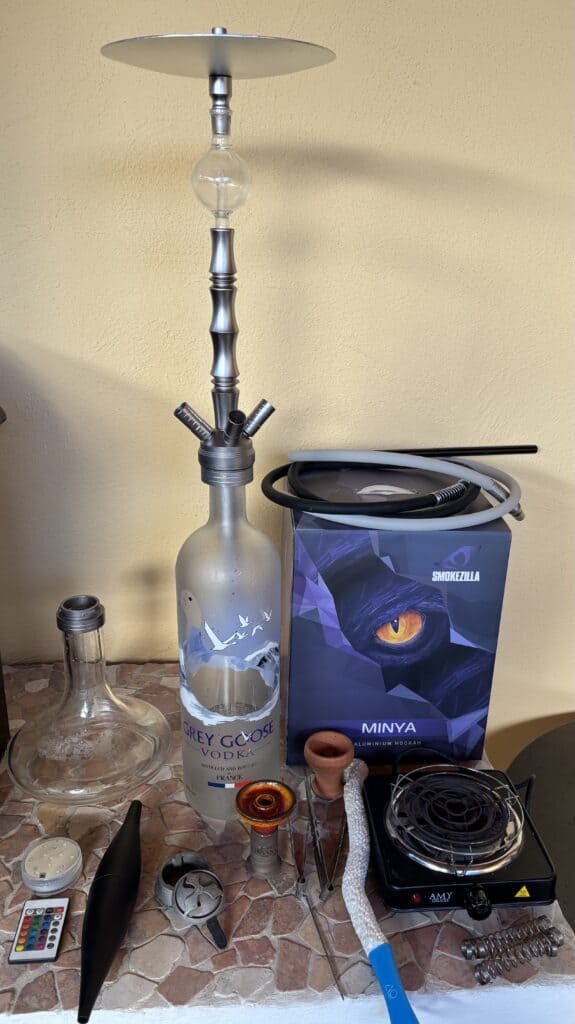 Verschiedene Shisha-Teile inklusive Glasbowl, Heizplatte und Zubehör.
