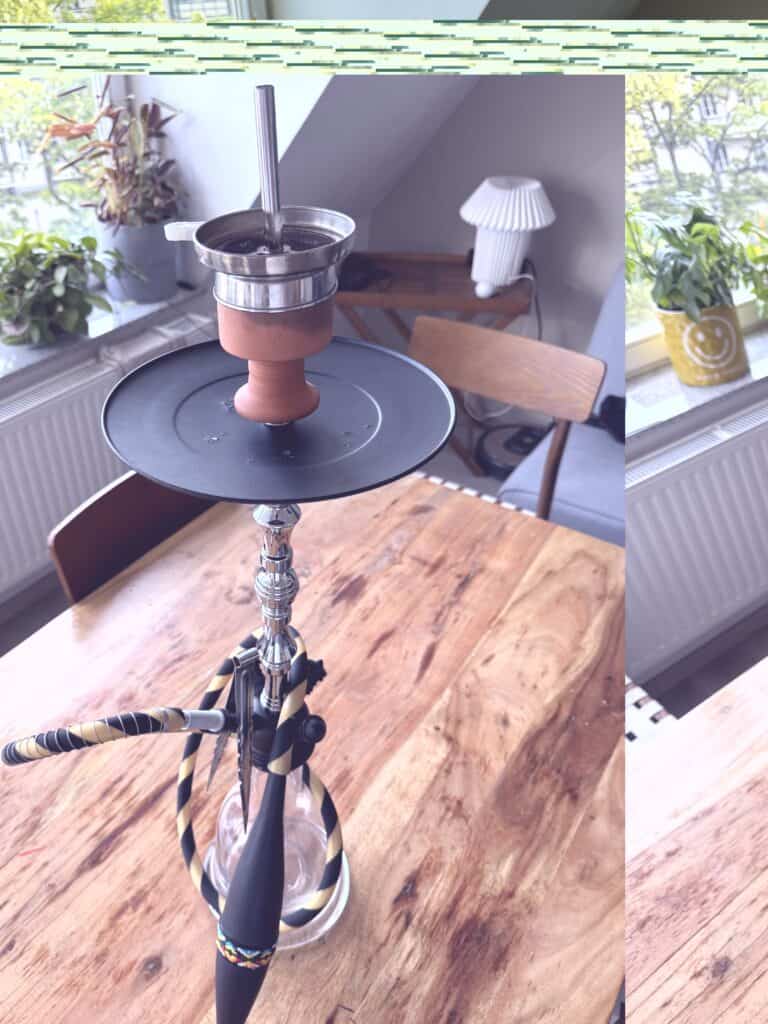 Rauchsäule mit Shisha-Kopf, geeignet für Wasserpfeifen, auf einem Holztisch im Raum.