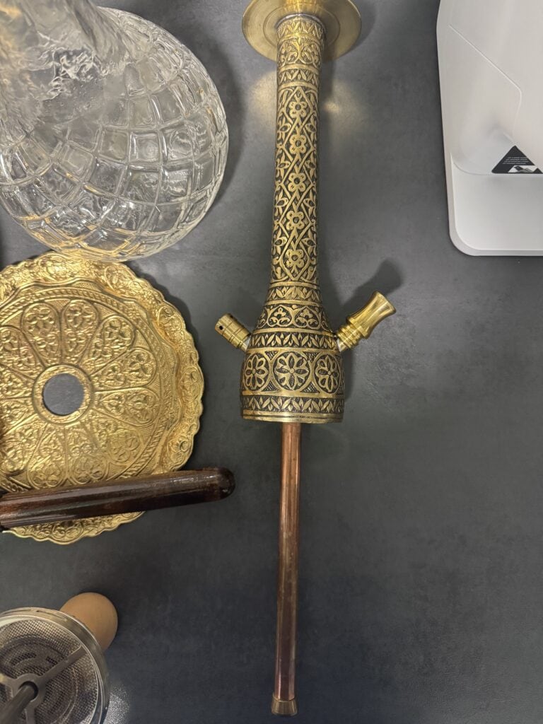 Detailaufnahme einer antiken Shisha-Pfeife mit goldener Verzierung und Glasbowl.