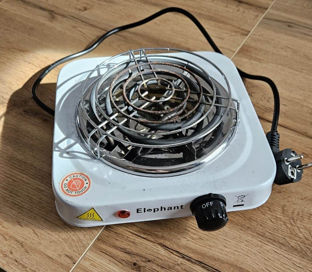 Kleines Elektrokochfeld mit Sicherheitsgitter und Drehregler.