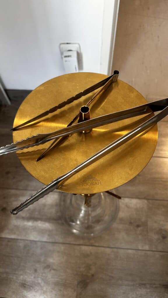Verschiedene Shisha-Zubehörteile auf einem goldenen Tablett.