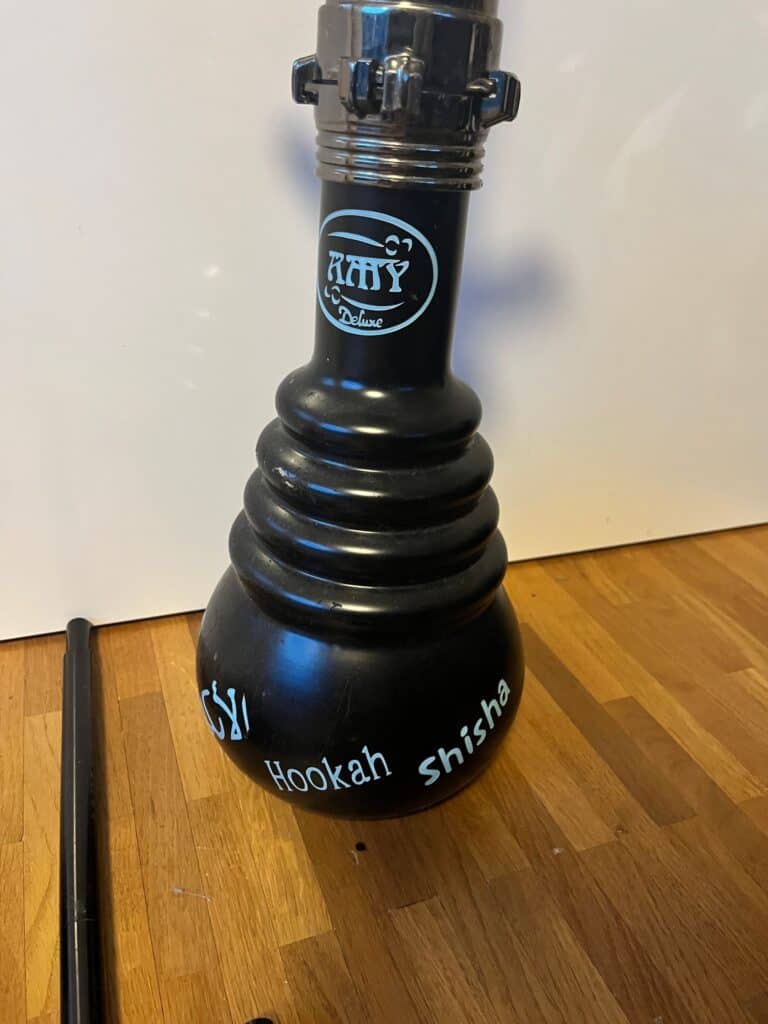 Schwarze Shisha mit Logo und Schriftzug auf Holzuntergrund.