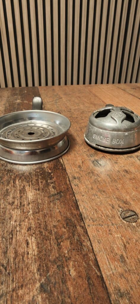 Rauchbox und Aschenbecher aus Metall auf Holzoberfläche.