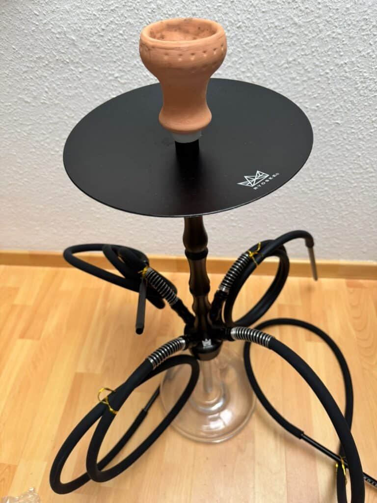 Shisha-Hookah mit Glasbowl und Schlauch, auf schwarzem Table.