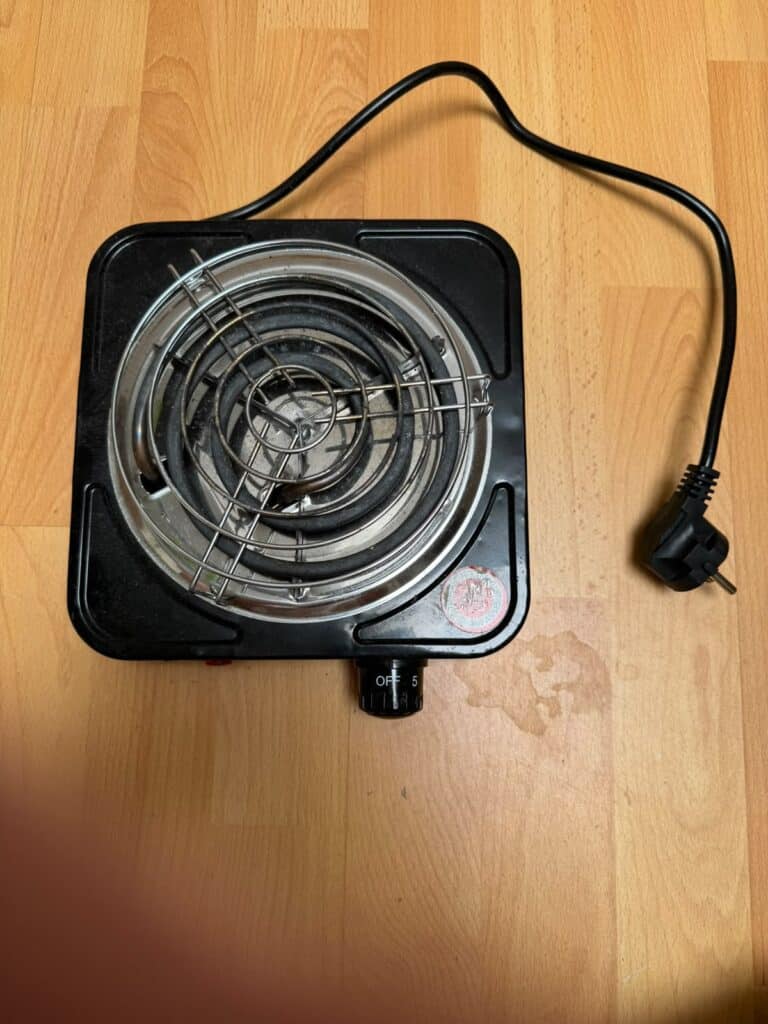 Kleiner elektrischer Heizstab mit Kabel und Schutzgitter.