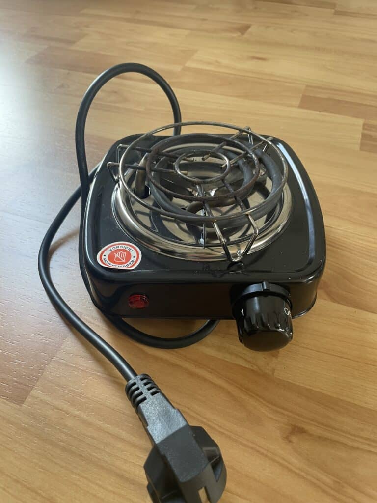 Herdplatte mit Kabel auf Holztisch, tragbare elektrische Kochplatte für Camping oder Zuhause.