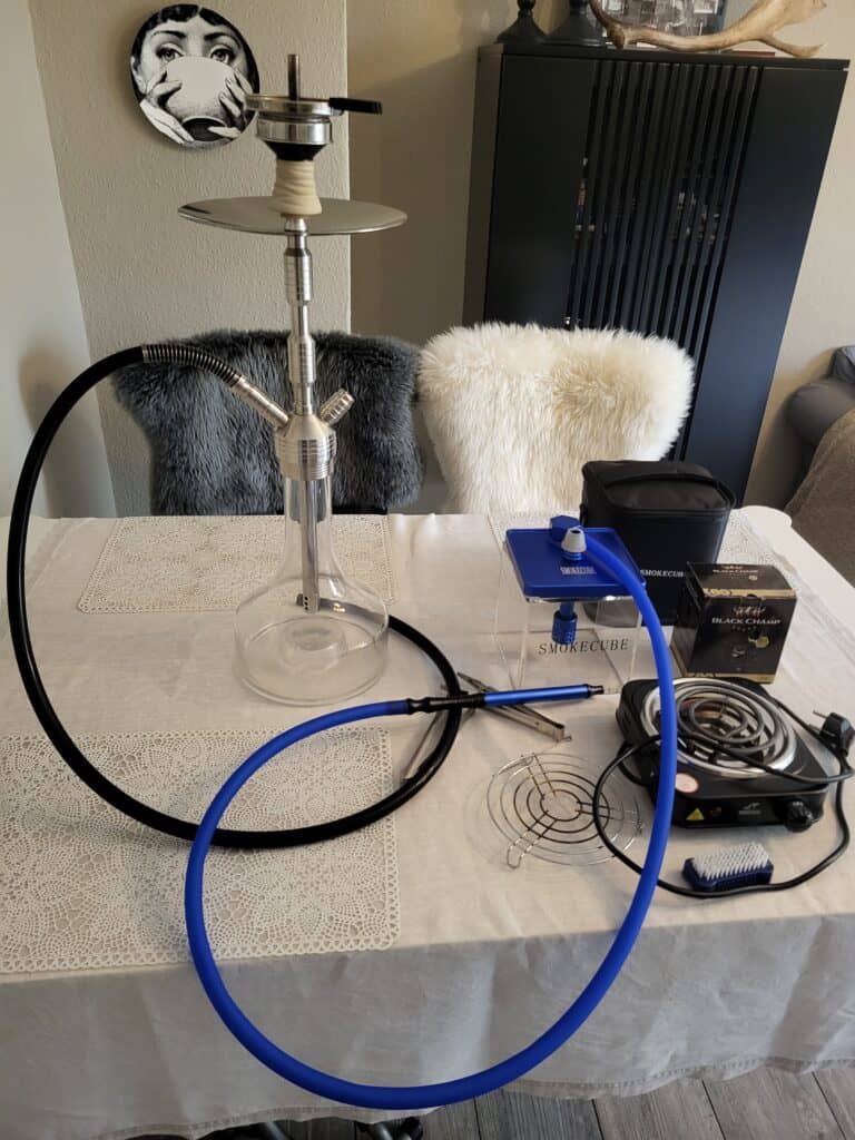Shisha mit Glasbowl, Heizsystem und Zubehör auf Esstisch.