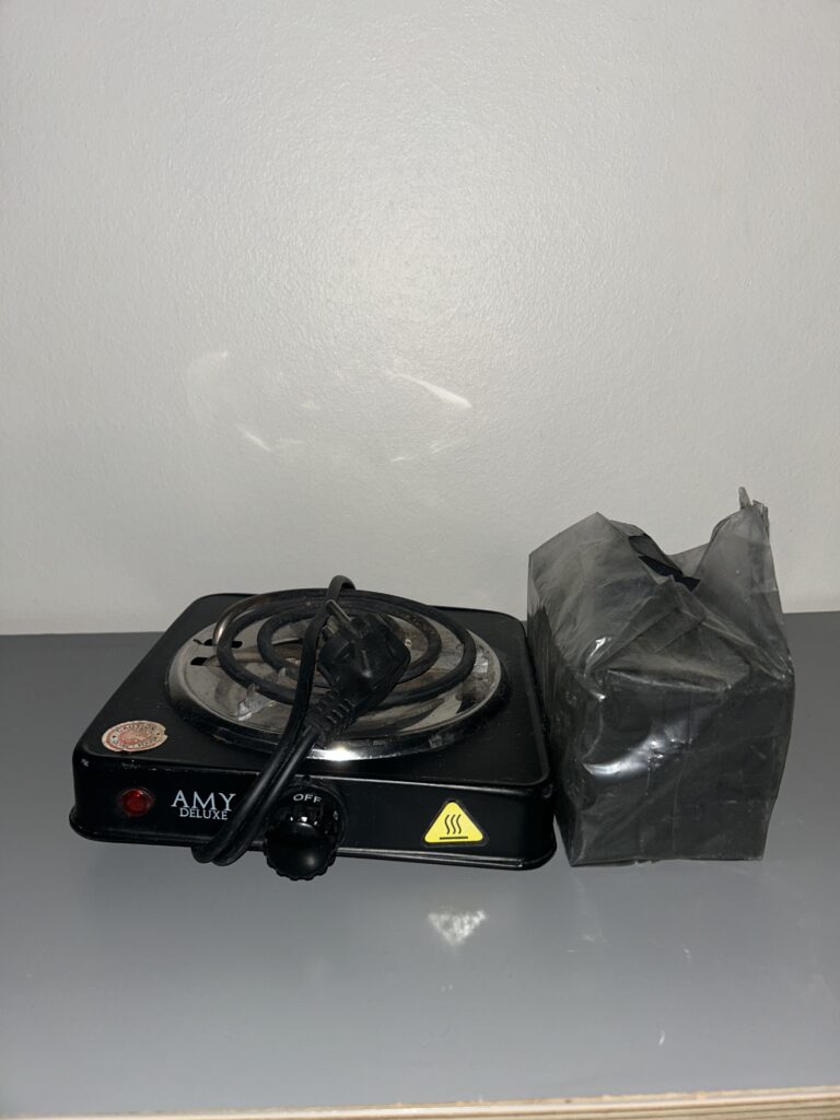 Kleine tragbare Herdplatte mit Kabel und Verpackung.