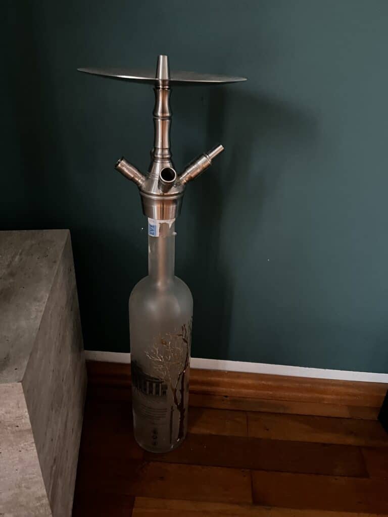 Wasserpfeife mit Metallkopf auf Glasflasche, ideal für Shisha-Liebhaber.