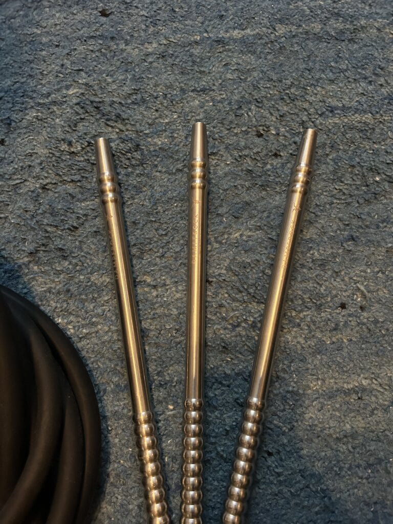 Drei Metallrohre für Shisha mit beaded Design, auf Asphalt.