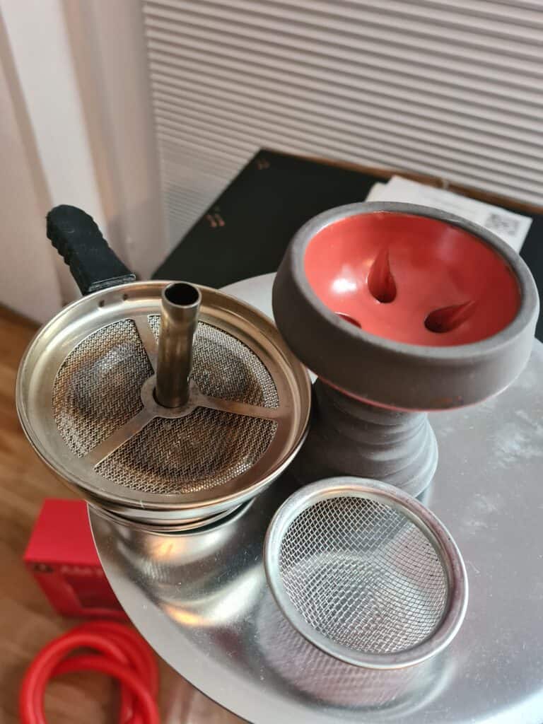 Shisha-Zubehör mit Keramikbowl, Sieb und Schlauch, bereit zum Rauchen.
