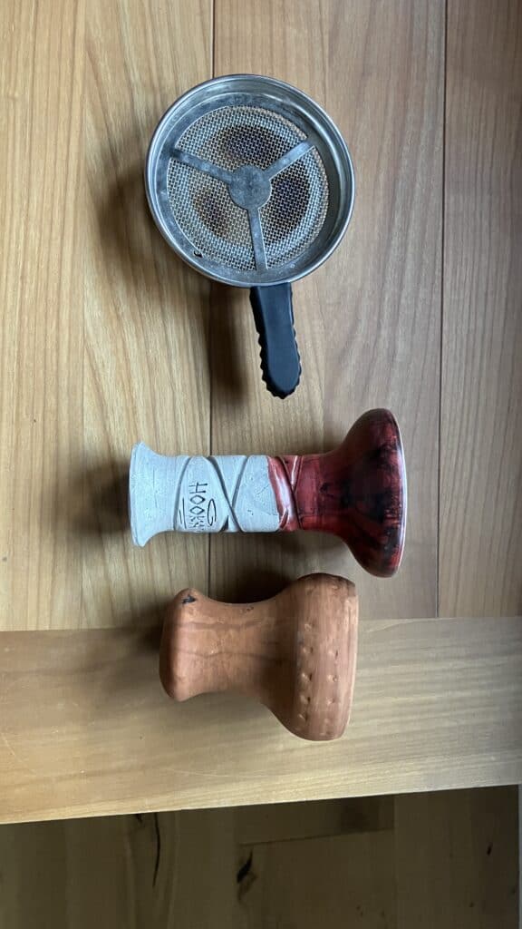 Sieb und zwei Mundstücke aus Holz und Kunststoff.