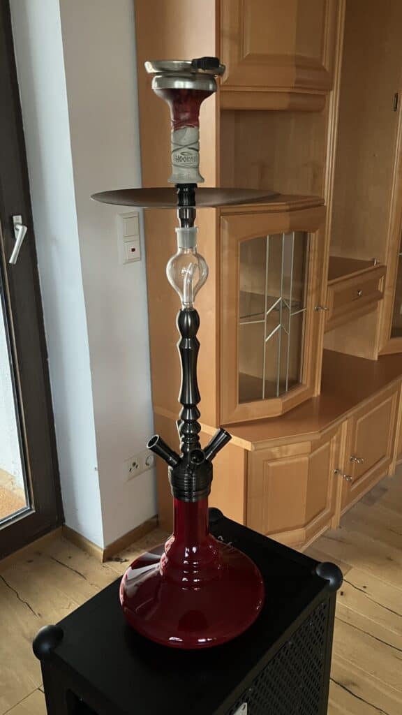 Shisha mit roter Glasbowl, Metallaufsatz und Schlauchanschluss.