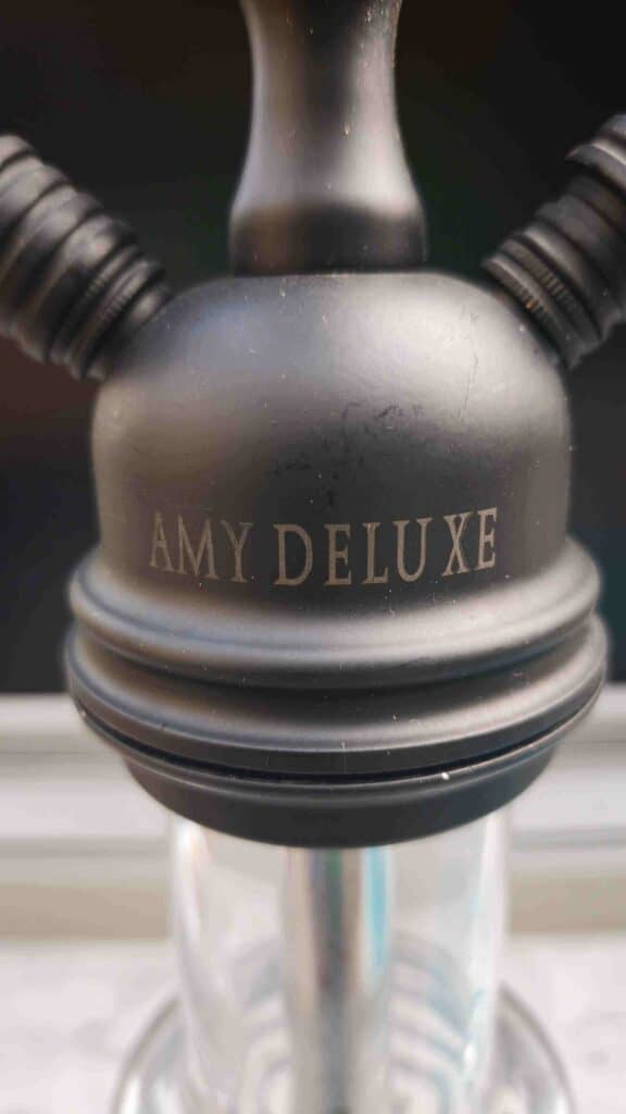 Schwarzer Amy Deluxe Shisha Kopf mit Silikonschläuchen.