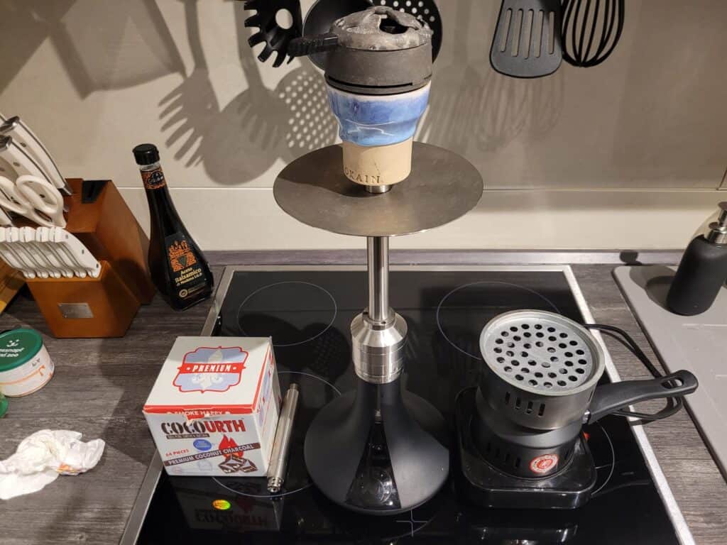 Shisha Glasbowl und Halter auf Herdplatte, Zubehör liegend.