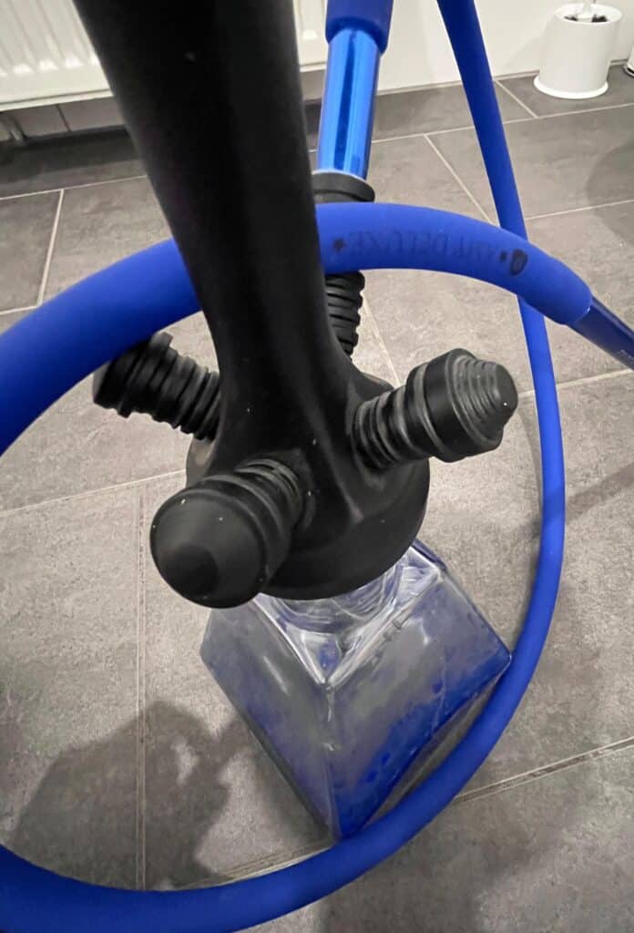 Shisha mit blauer Silikonschlauch und Glasbowl auf Fliesenboden.