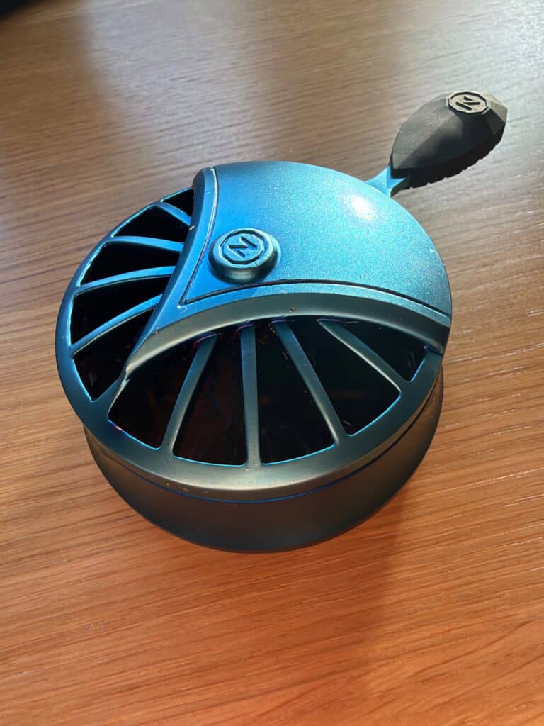 Kleiner blauer elektrischer Ventilator auf Holzoberfläche.