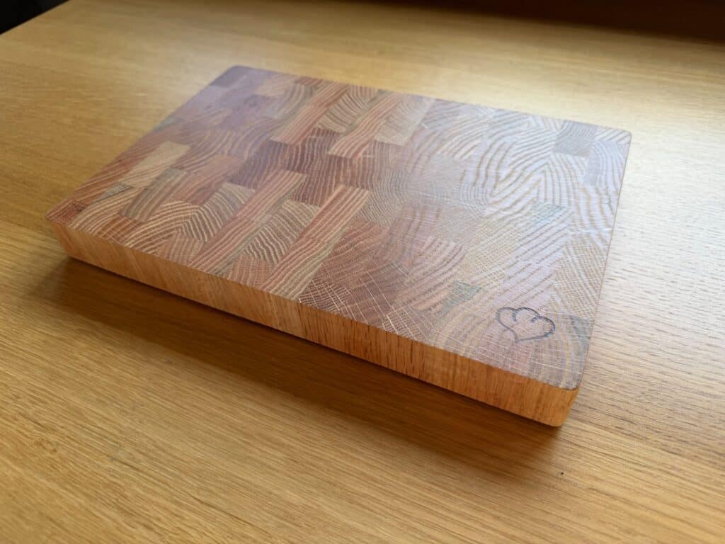 Holzschneidebrett mit Herz-Design auf Holzoberfläche.