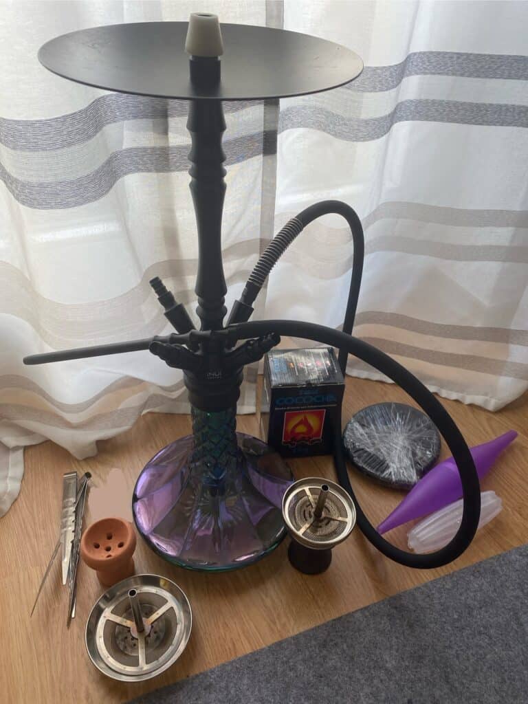 Shisha mit Zubehör, Tabak und Kohle auf Holztisch.