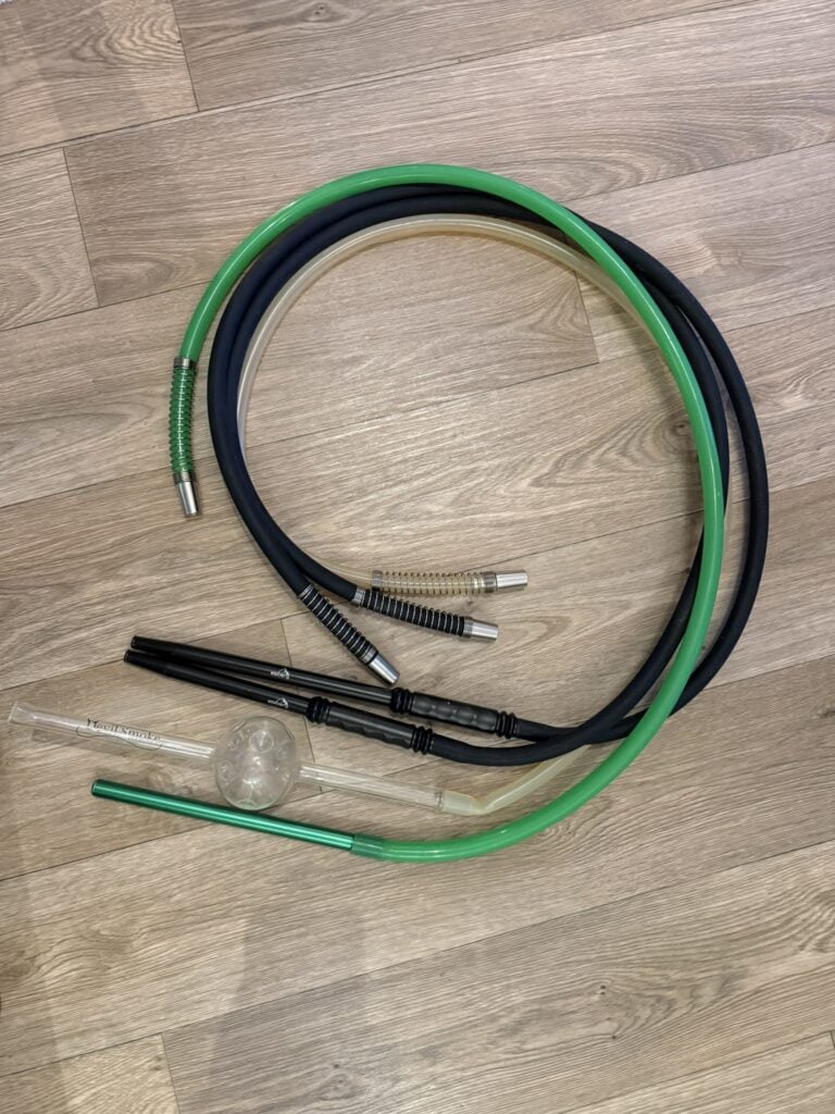 Schwarzer und grüner Shisha Schlauch mit Glasbowl auf Holzboden.